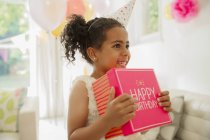 Eager girl holding birthday gift — Stock Photo