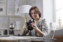 Femme photographe utilisant un appareil photo numérique au bureau — Photo de stock