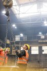 Steel workers looking up at crane chain in factory — Stock Photo