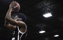 Joven jugador de baloncesto enfocado a disparar la pelota en el gimnasio - foto de stock