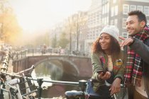 Jeune couple avec vélos sur pont urbain au-dessus du canal, Amsterdam — Photo de stock