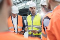Male foreman, engineers and construction workers meeting at construction site — Stock Photo