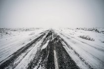 Perspectiva decrescente estrada coberta de neve remota — Fotografia de Stock