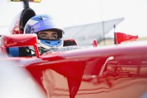 Fórmula focada um piloto de carro de corrida usando capacete, olhando para longe — Fotografia de Stock