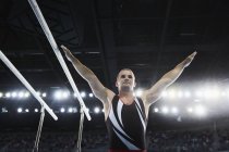 Мужчина гимнаст с поднятыми руками рядом с параллельными брусьями — стоковое фото