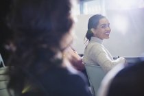Lächelnde Geschäftsfrau dreht sich um, blickt im Konferenzpublikum zurück — Stockfoto