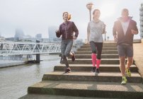 Läufer laufen die Treppe entlang der sonnigen städtischen Uferpromenade hinunter — Stockfoto