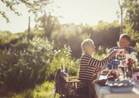Couple toasting verres à vin à la table de patio de fête de jardin ensoleillé — Photo de stock