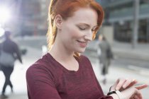 Крупним планом усміхнена жінка бігунка перевіряє розумний годинник — стокове фото