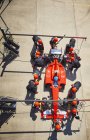 Overhead pit crew working on formula one race car in pit lane — Stock Photo