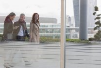 Gente de negocios caminando en balcón urbano de gran altura - foto de stock