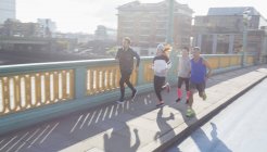 Runners running on sunny urban bridge — Stock Photo