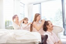 Family fixing each others hair in a row — Stock Photo