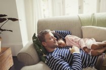 Carinhoso, sereno pai multi-étnico e filha cochilando no sofá — Fotografia de Stock