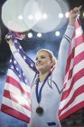 Улыбающаяся гимнастка празднует победу с американским флагом — стоковое фото