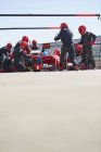 Команда пит-стопа заменяет шины на болиде Формулы-1 в пит-лейн — стоковое фото