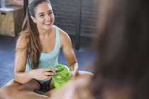 Smiling young woman drinking water and resting post workout — Stock Photo