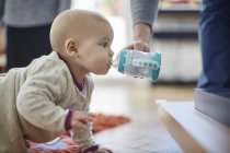 Baby girl crawling and drinking from sip cup — Stock Photo