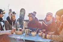 Amigos snowboarder tomando cócteles en el soleado balcón apres-ski - foto de stock