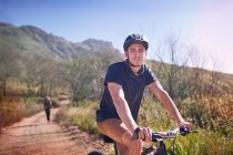 Retrato jovem mountain bike em remoto, trilha ensolarada — Fotografia de Stock