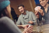 Friends playing cards at table in cabin — Stock Photo