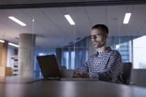 Бизнесмен, работающий допоздна за ноутбуком в офисе — стоковое фото
