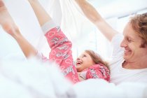 Padre e figlia che giocano sul letto — Foto stock