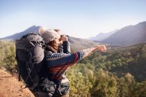 Giovane coppia escursionismo, guardando la vista soleggiata con binocolo — Foto stock