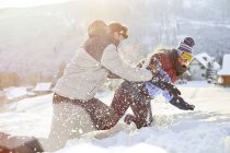 Playful couple enjoying snowball fight in snowy field — Stock Photo