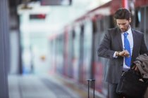 Бізнесмен перевіряє годинник на вокзалі — стокове фото
