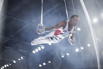Gymnaste masculin effectuant sur les anneaux de gymnastique dans l'arène — Photo de stock