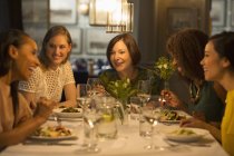 Mulheres sorridentes amigos jantando na mesa do restaurante — Fotografia de Stock