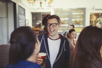 Чоловік сміється і п'є пиво з друзями в барі — стокове фото