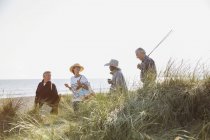 Senior coppie con canna da pesca a piedi in erba soleggiata spiaggia — Foto stock