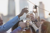 Enthusiastic young adults toasting cocktails at rooftop party — Stock Photo
