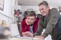 Male carpenters working at laptop in workshop — Stock Photo