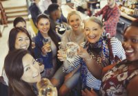 Retrato sonriente, seguro de las mujeres amigos tostando cerveza y copas de vino en el bar - foto de stock