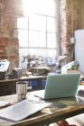 Laptop, Kaffee und Klemmbrett auf Werkbank in Werkstatt — Stockfoto