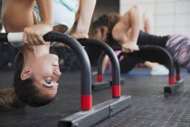 Fokussierte junge Frau macht kopfüber stehenden Schulterstand mit Geräten im Fitnessstudio — Stockfoto