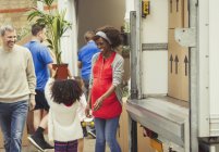 Multi-ethnic young family unloading moving van outside new house — Stock Photo