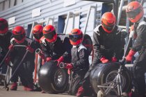 Pit crew ready with tires in formula one pit lane — Stock Photo