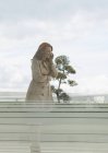 Улыбающаяся деловая женщина с рыжими волосами разговаривает по мобильному телефону на балконе — стоковое фото