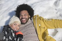 Portrait of happy couple laying in snow — Stock Photo