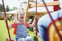 Menina alegre rindo no carrossel no parque de diversões — Fotografia de Stock
