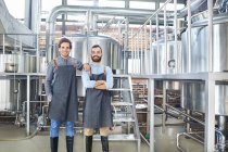 Portrait smiling male brewers in aprons near vats — Stock Photo