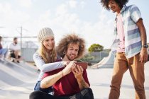 Friends using smart phone at sunny skate park — Stock Photo