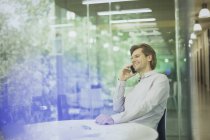 Улыбающийся бизнесмен разговаривает по мобильному телефону в конференц-зале — стоковое фото