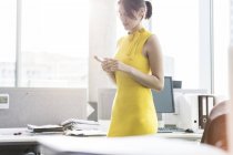 Бізнес-леді смс з мобільним телефоном в офісі — стокове фото