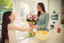 Affectionate daughter giving flower bouquet to mother on Mothers Day — Stock Photo