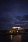Casa flotante de verano iluminado en el océano noche - foto de stock